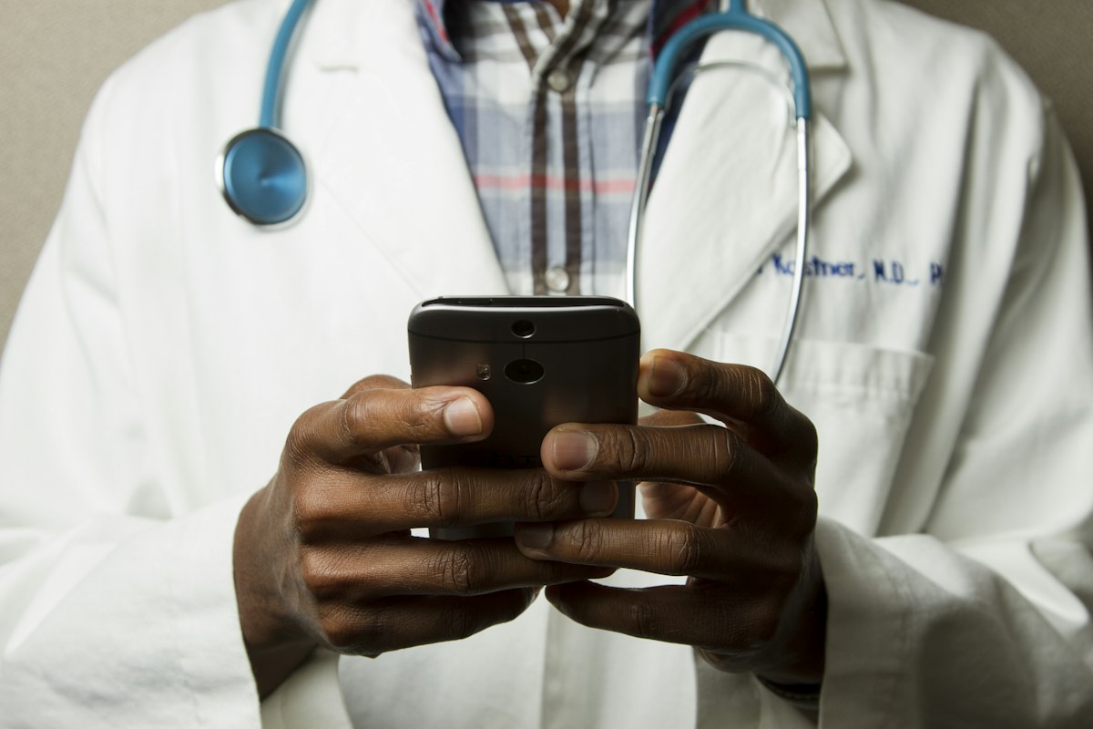 Medical professional in a white coat using a smartphone