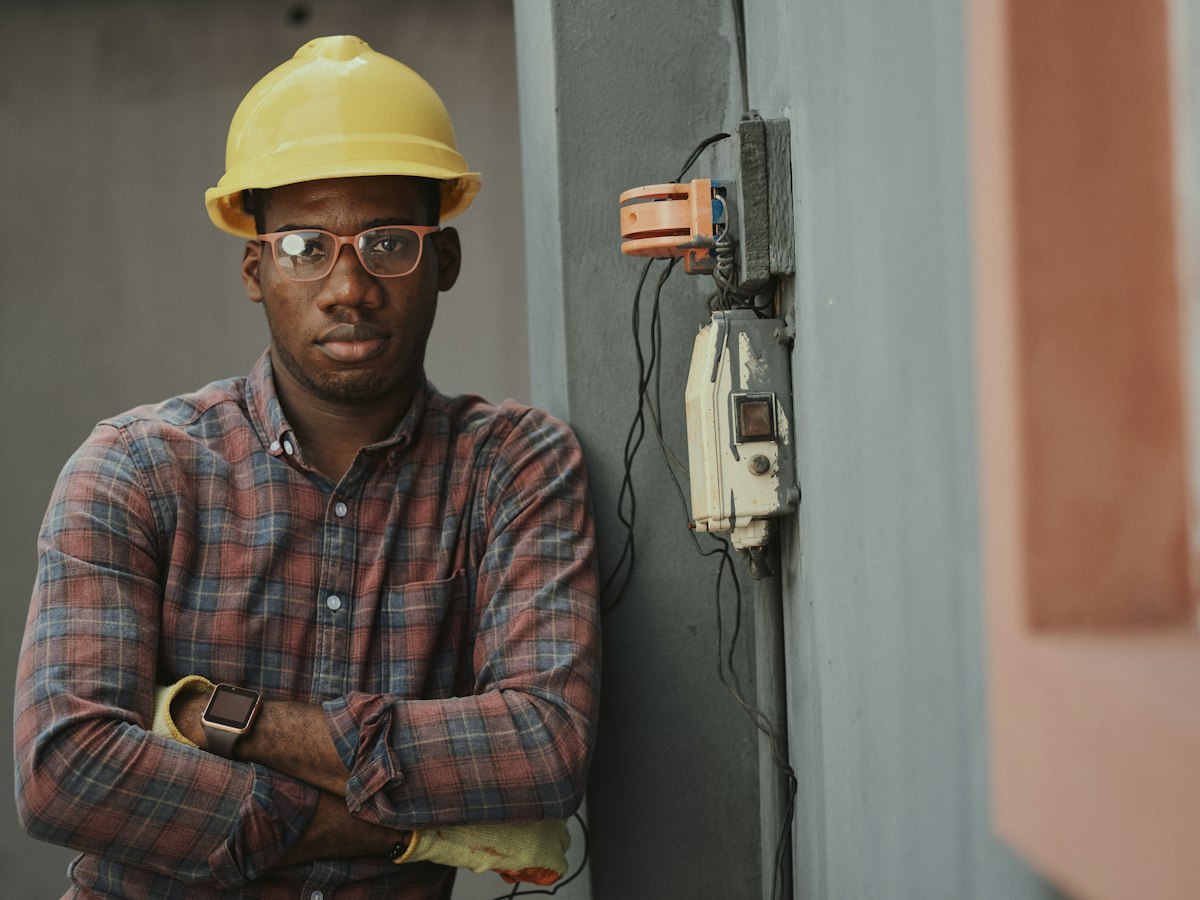 Electrician in safety equipment standing beside electrical equipment