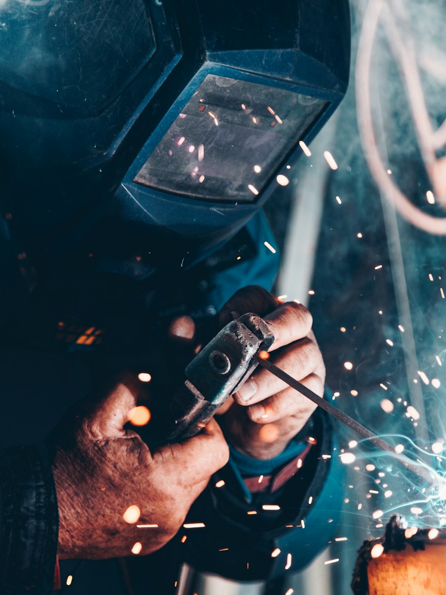 Welder wearing protective equipment while working on a metal component